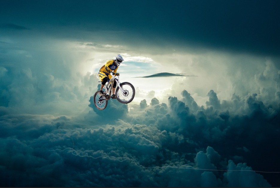 A man on bicycle floating in the mid in cloudy bachdrop